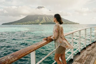 Femme admirant le lagon turquoise de Polynésie française depuis le pont d'un bateau de croisière