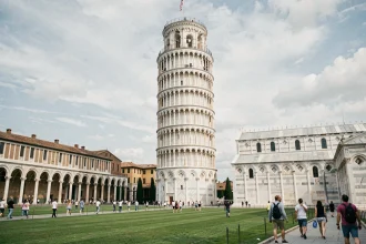 Vue grand angle de la Tour de Pise inclinée sur la Piazza dei Miracoli entourée de pelouses vertes et de touristes